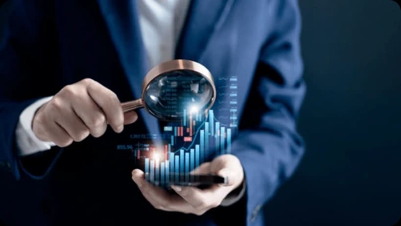 Businessman examining glowing holographic financial bar chart with magnifying glass.